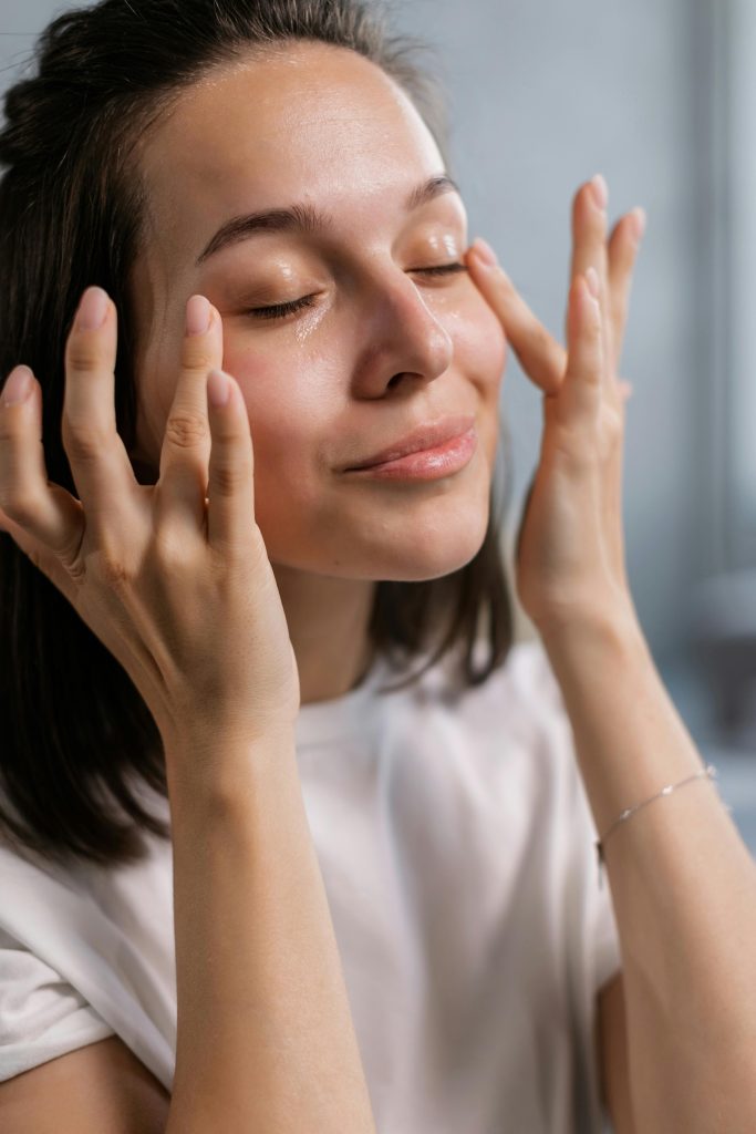 Jeune femme appliquant de la crème de soin avec un sourire, mettant en avant les routines de beauté et de soin de soi