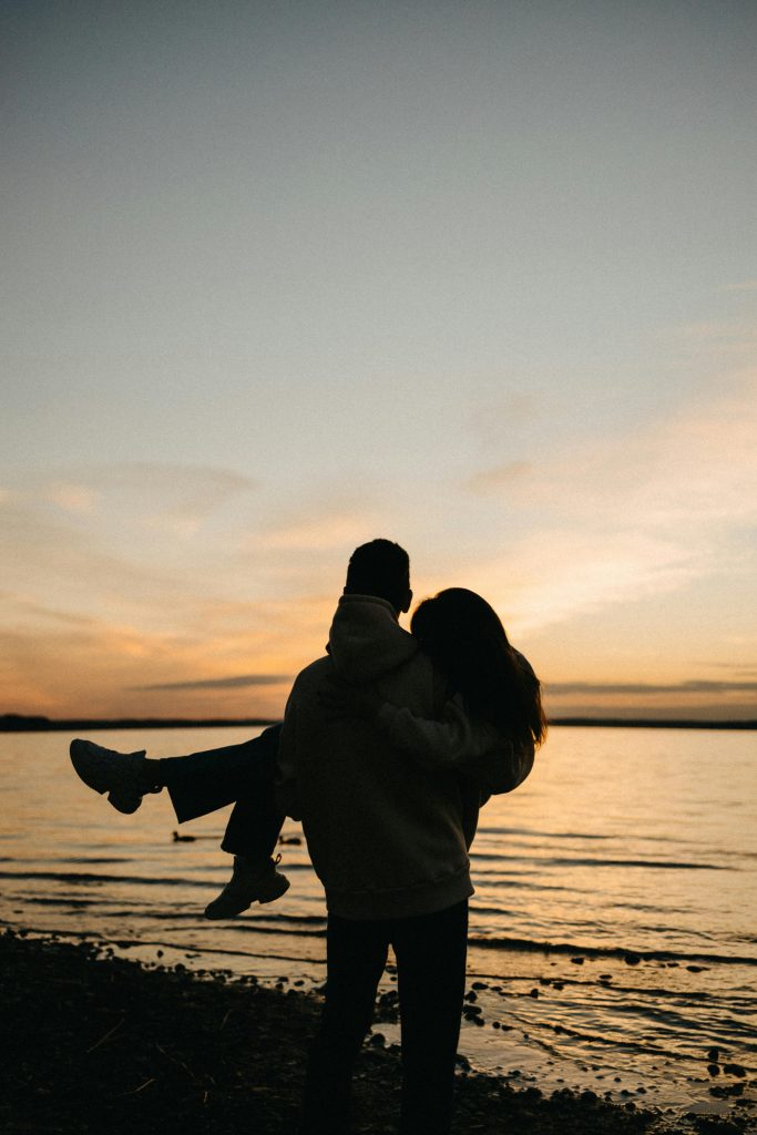 A silhouette romantique d'un couple à la plage lors d'un coucher de soleil serein, embrassant l'amour et la tranquillité.