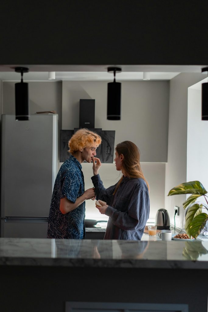Un couple partage un moment tendre dans une cuisine élégante, mettant en avant l'amour et la complicité.
