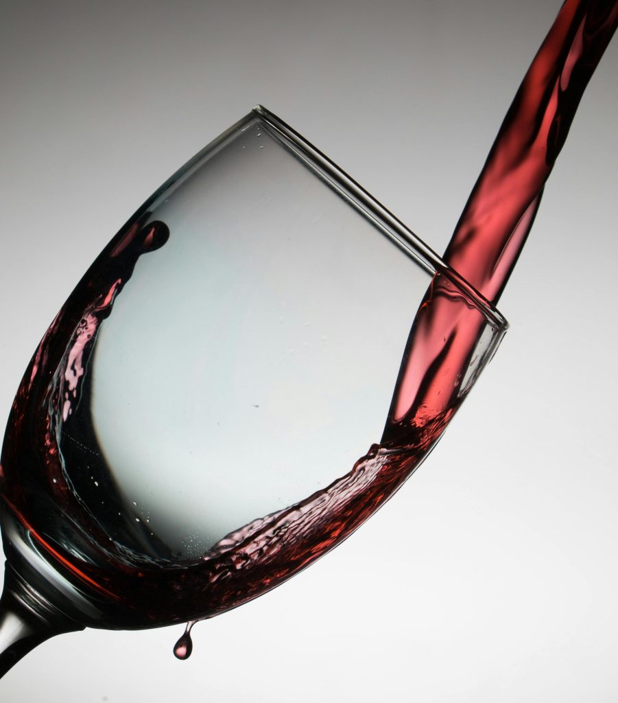 Dramatique versement de vin rouge dans un verre incliné, mettant en valeur l'élégance et le flux