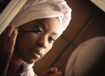 Une femme qui se met du mascara devant un miroir